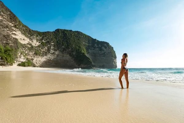 Travel around the world. Girl wearing swimsuit and staying on the beach