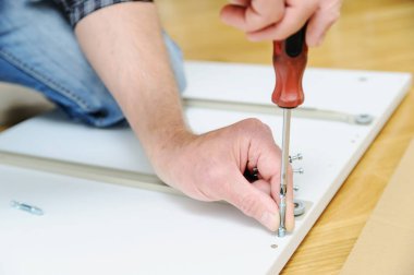 Bir adam bağlayıcı ortak cıvata mobilya Yönetim Kurulu yüklüyor.