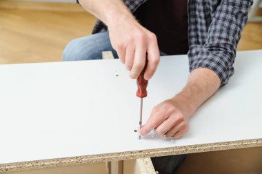 Bir adam bağlayıcı ortak cıvata mobilya Yönetim Kurulu yüklüyor.