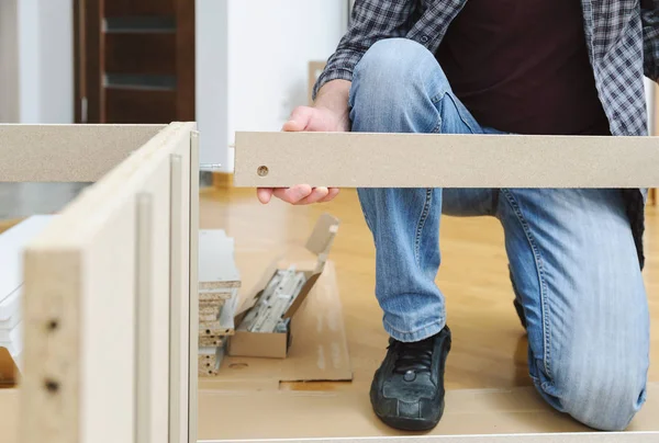 一个男人正在组装家具从纸板板 — 图库照片