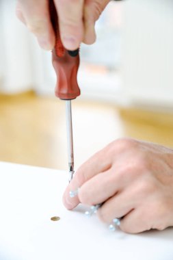 Bir adam bağlayıcı ortak cıvata mobilya Yönetim Kurulu yüklüyor.