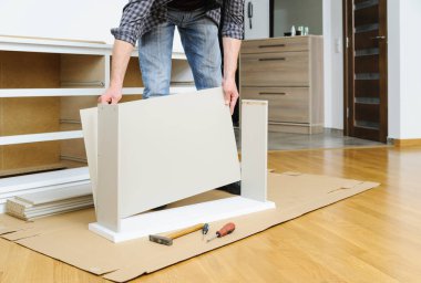 Komodinin montaj. Bir adam çekmeceyi parçalarını birleştiren hattır.