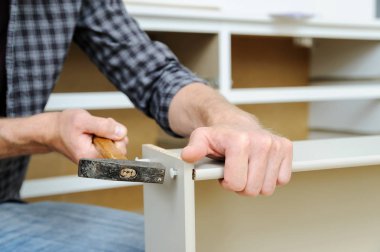 Komodinin montaj. Bir adam bir çekiç çekmece'nın panoları düzeltmek için kullanma.