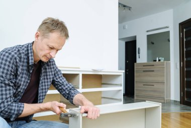 Çekmece sandığını monte ediyorum. Adam çekmeceyi tamir etmek için çekiç kullanıyor..