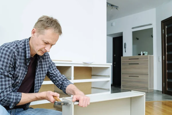 Çekmece sandığını monte ediyorum. Adam çekmeceyi tamir etmek için çekiç kullanıyor..