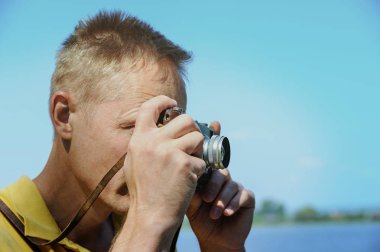 Adam arka plan ağaç ve göl üzerinde eski bir kamera fotoğraf çekimi.