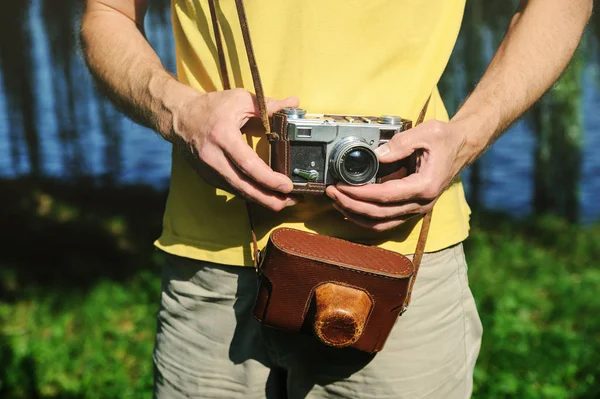 A man is holding a vintage camera. One of his hand is setting the lens.