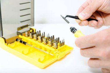 Bir adam bir cımbız biraz bir tornavida eklemek için kullanıyor. Sonraki bit bir dizi olduğunu.