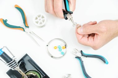 Bir adam pense süs bir gümüş tel oluşturmak için kullanıyor. El yapımı takı.