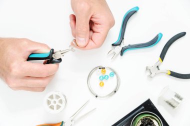 Bir adam pense süs bir gümüş tel oluşturmak için kullanıyor. El yapımı takı.