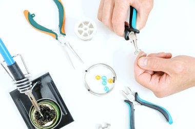 Bir adam pense süs bir gümüş tel oluşturmak için kullanıyor. El yapımı takı.