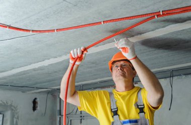Elektrikçi elektrik bir oluklu boru tavana sabitleme.