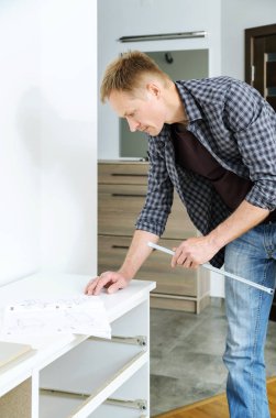 Komodinin montaj. Adam bir yönerge mobilya montaj için arıyor.