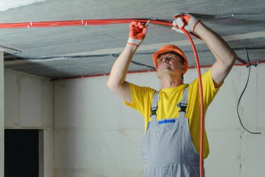 Elektrikçi elektrik bir oluklu boru tavana sabitleme.