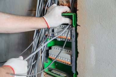 Elektrikçi elektrik telleri bir anahtarlama sigorta kutusuna yüklüyor.