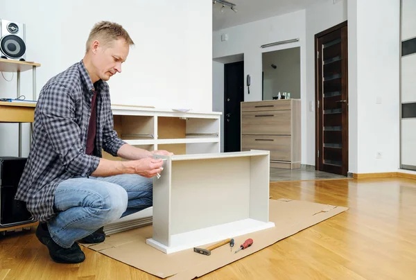 Mounting the chest of drawers. The man is joining the pieces of the drawer.