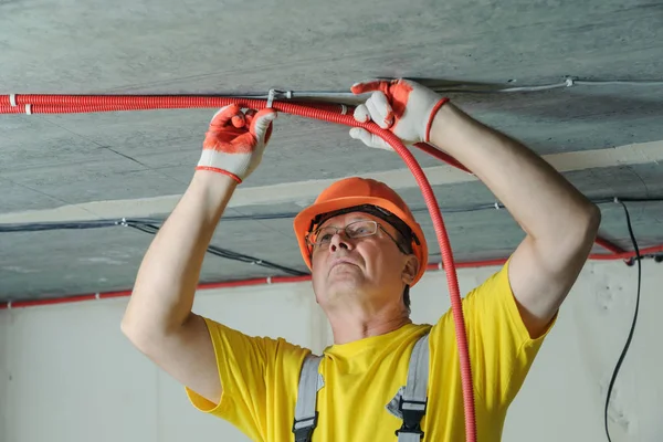 電気技師は 天井に電気のコルゲート チューブを修正します — ストック写真