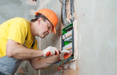 Elektrikçi sigortalar anahtarı kutusuna yüklüyor.