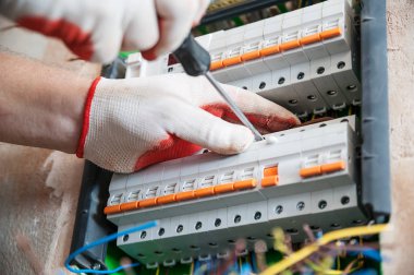 Bir elektrikçi sigortalar anahtarı kutusuna yüklüyor.