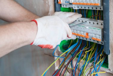 Bir elektrikçi sigortalar anahtarı kutusuna yüklüyor.