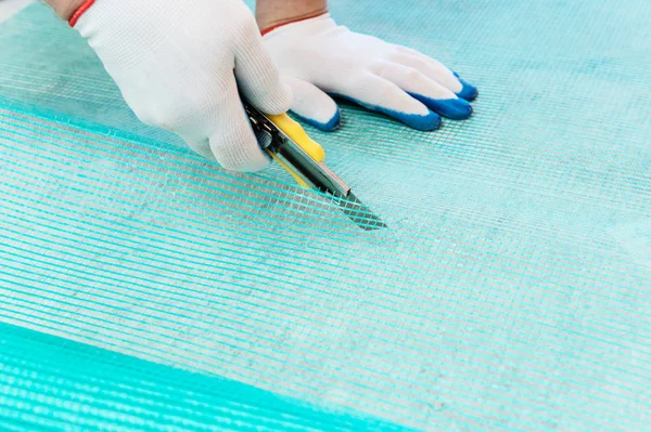 Ein Arbeiter Schneidet Mit Einem Messer Ein Stück Glasfasernetz — Stockfoto