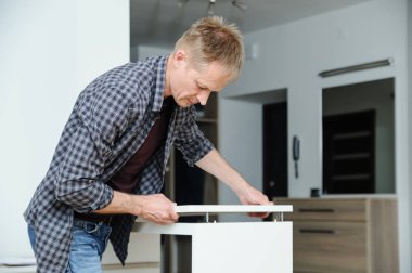 Adam mobilya evde toplanır. Komodinin üstünde ayarlar.