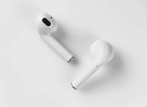 Beyaz bir arka plan üzerinde beyaz kablosuz kulaklıklar vardır. Makro.