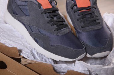 Beyaz kağıt üzerinde gri spor ayakkabı.