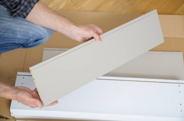 Bir adam bir mobilya yönetim kurulu tutuyor.