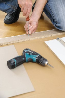 Bir adam evde mobilya montaj.