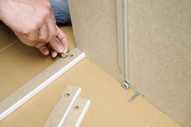 Bir adam evde mobilya montaj.