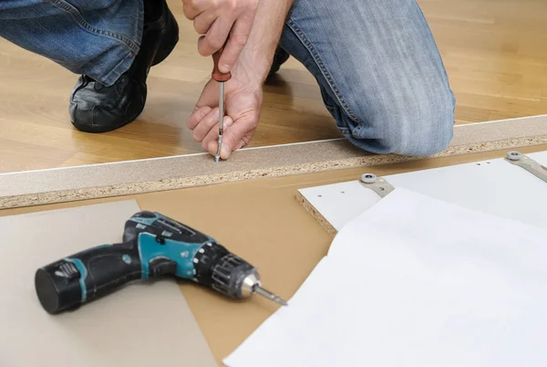 Un hombre está montando los muebles en casa . —  Fotos de Stock