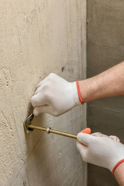 Een werknemer is het repareren van een muur van bouten. — Stockfoto