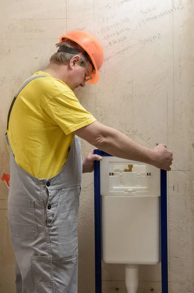 De werknemer is het monteren van een ingebouwde WC-tank. — Stockfoto
