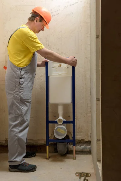 The worker is mounting a built-in toilet tank.