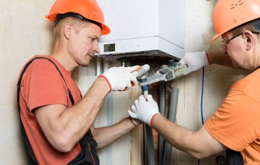 İşçiler gaz kazanının plastik borularını lehimleme.