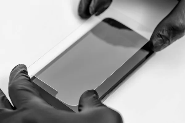 Een man houdt een beschermend glas van een smartphone. — Stockfoto