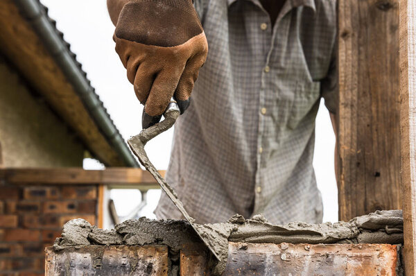 A worker is applying a mortar with a trowel to the brick.