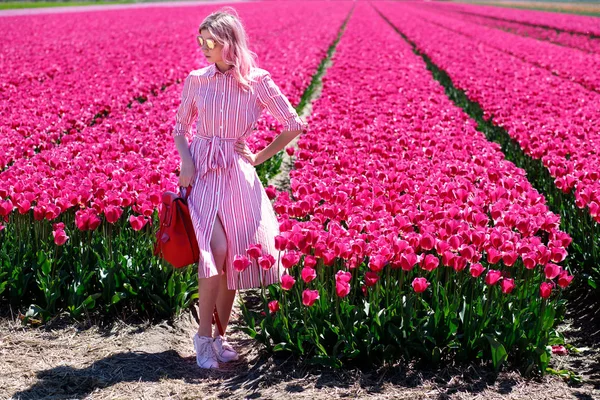 Smiling teenage girl walks through tulip field — Stock Photo, Image