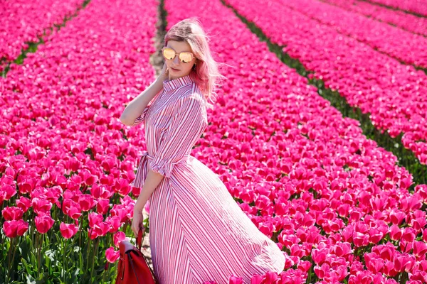 Smiling teenage girl walks through tulip field — Stock Photo, Image