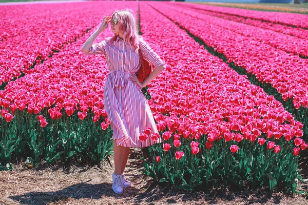 Sorrindo adolescente menina caminha através de campo de tulipa — Fotografia de Stock