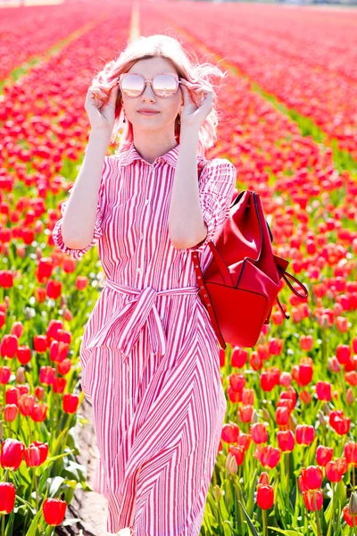 Sorrindo adolescente menina caminha através de campo de tulipa — Fotografia de Stock