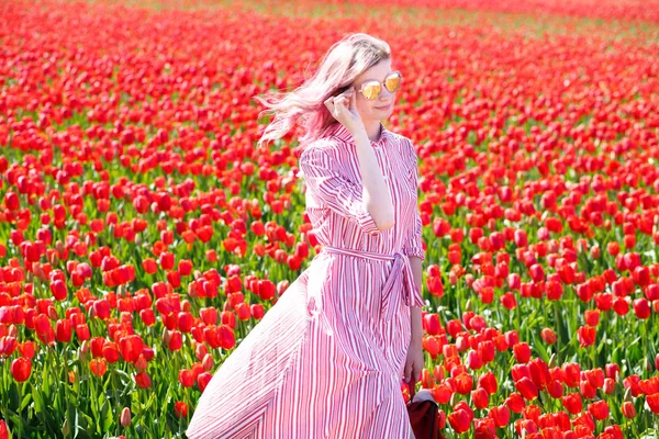 Smiling teenage girl walks through tulip field — Stock Photo, Image