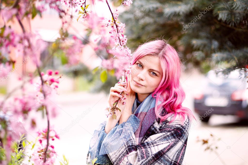 young beautiful girl with pink hair standing near a tree with flowers, pink flowers, spring, sun, happiness, tenderness