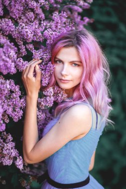 Pembe saçlı güzel kız leylak Bahçe zevk. neşeli genç temiz havada yürüyüş. yumuşak ışık stil rengini.