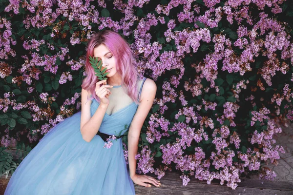 Fine art portrait of girl in beautiful dress in lilac garden