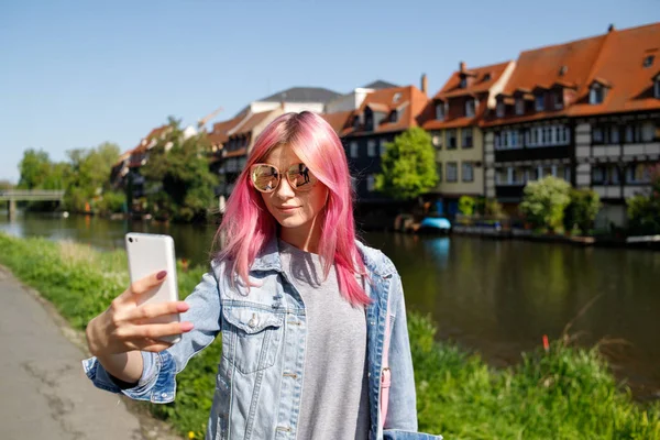 女旅行者将在你的手机上为 Instagram 或其他社交网络在老城区的背景上拍一张自拍照片 — 图库照片