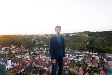 takım elbiseli bir adam gözlem güverte üzerinde duruyor ve tarihi eski şehir Pottenstein Almanya yukarıda eski kasaba evleri görünümünü bakar.