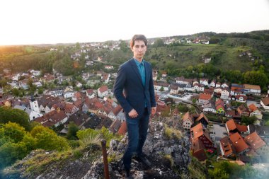 takım elbiseli bir adam gözlem güverte üzerinde duruyor ve tarihi eski şehir Pottenstein Almanya yukarıda eski kasaba evleri görünümünü bakar.