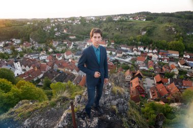 takım elbiseli bir adam gözlem güverte üzerinde duruyor ve tarihi eski şehir Pottenstein Almanya yukarıda eski kasaba evleri görünümünü bakar.